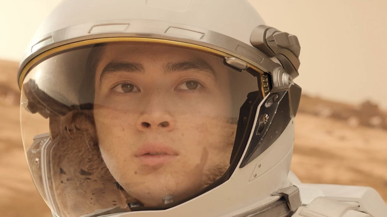 An astronaut in a helmet, gazing into the distance on a barren planet