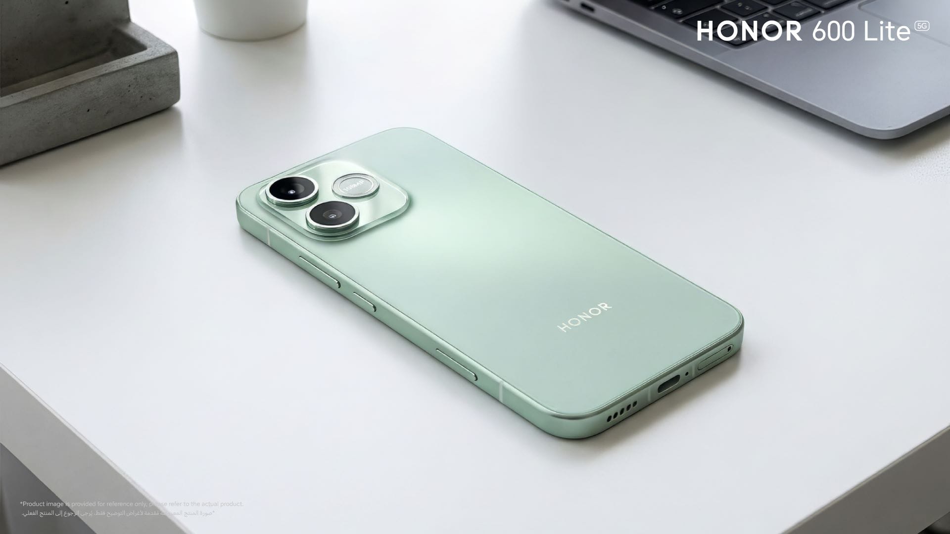 HONOR 600 Lite smartphone in mint green color on a desk with a laptop, showcasing dual rear cameras.