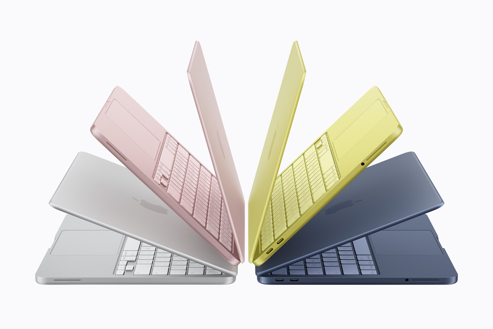 Four Apple laptops in pastel colors arranged in a fan shape.