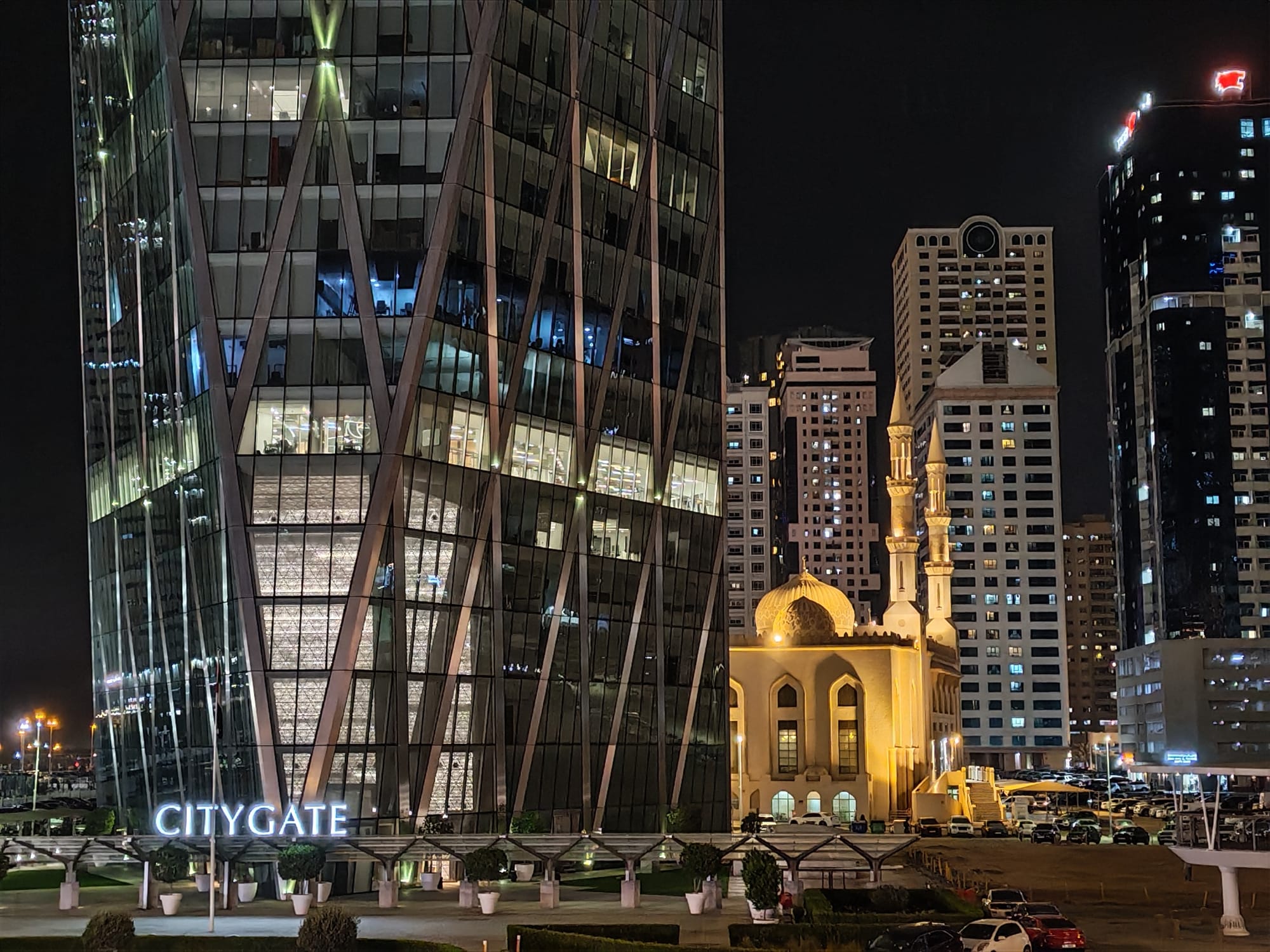 Honor 600 night camera sample: CityGate tower in Sharjah next to an illuminated mosque, with apartment towers behind