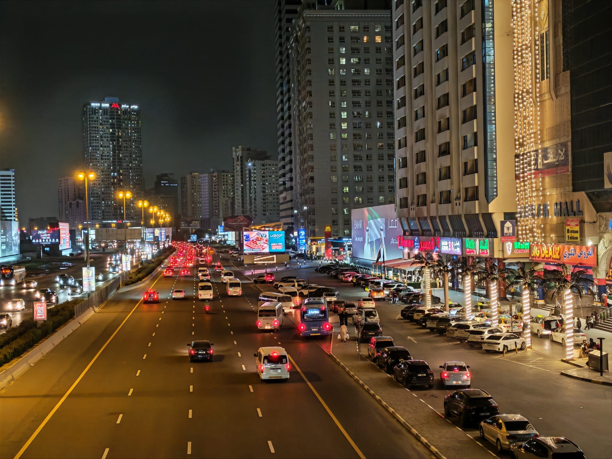 Honor 600 night camera sample: busy Sharjah street with car light trails and illuminated mall signage