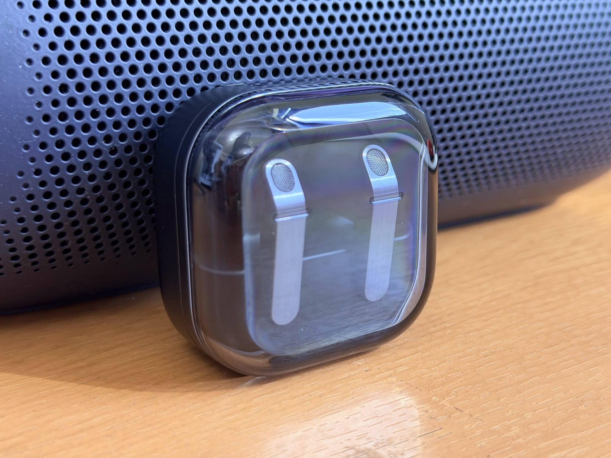 Samsung Galaxy Buds4 Pro charging case placed on wooden surface with a textured background.