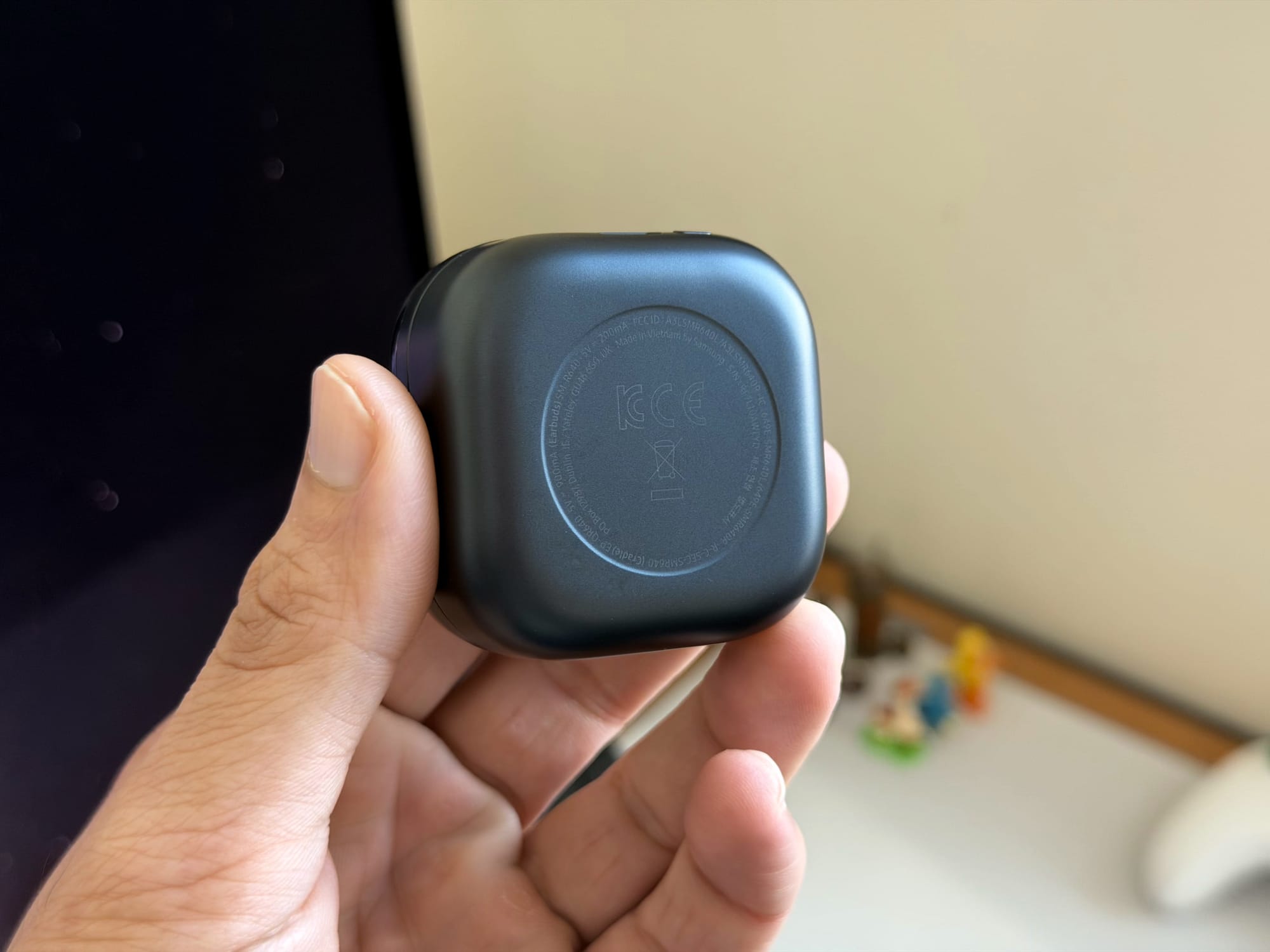 Hand holding the charging case for Samsung Galaxy Buds4 Pro.