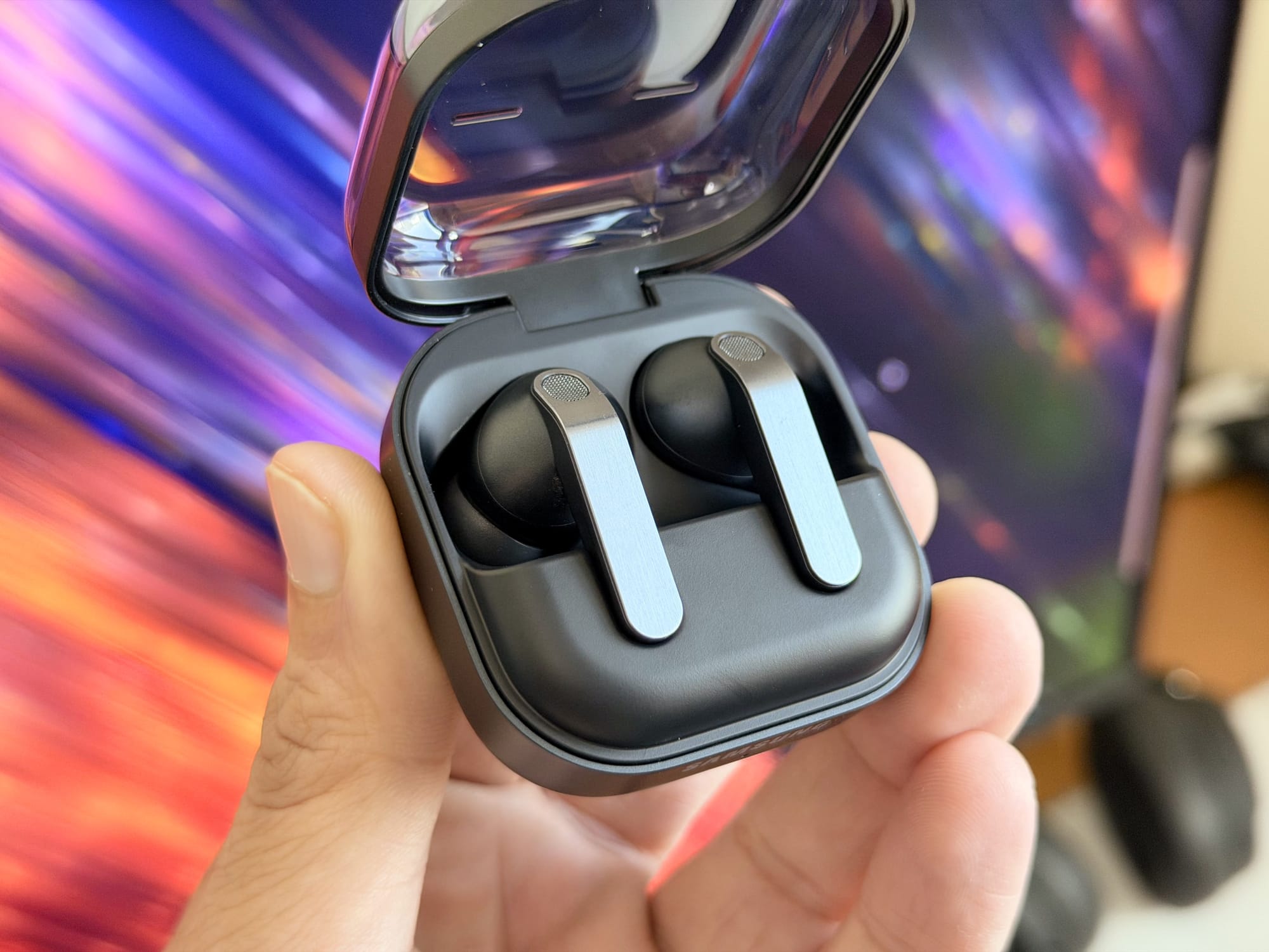 Hand holding Samsung Galaxy Buds4 Pro charging case open, showcasing earbuds inside.