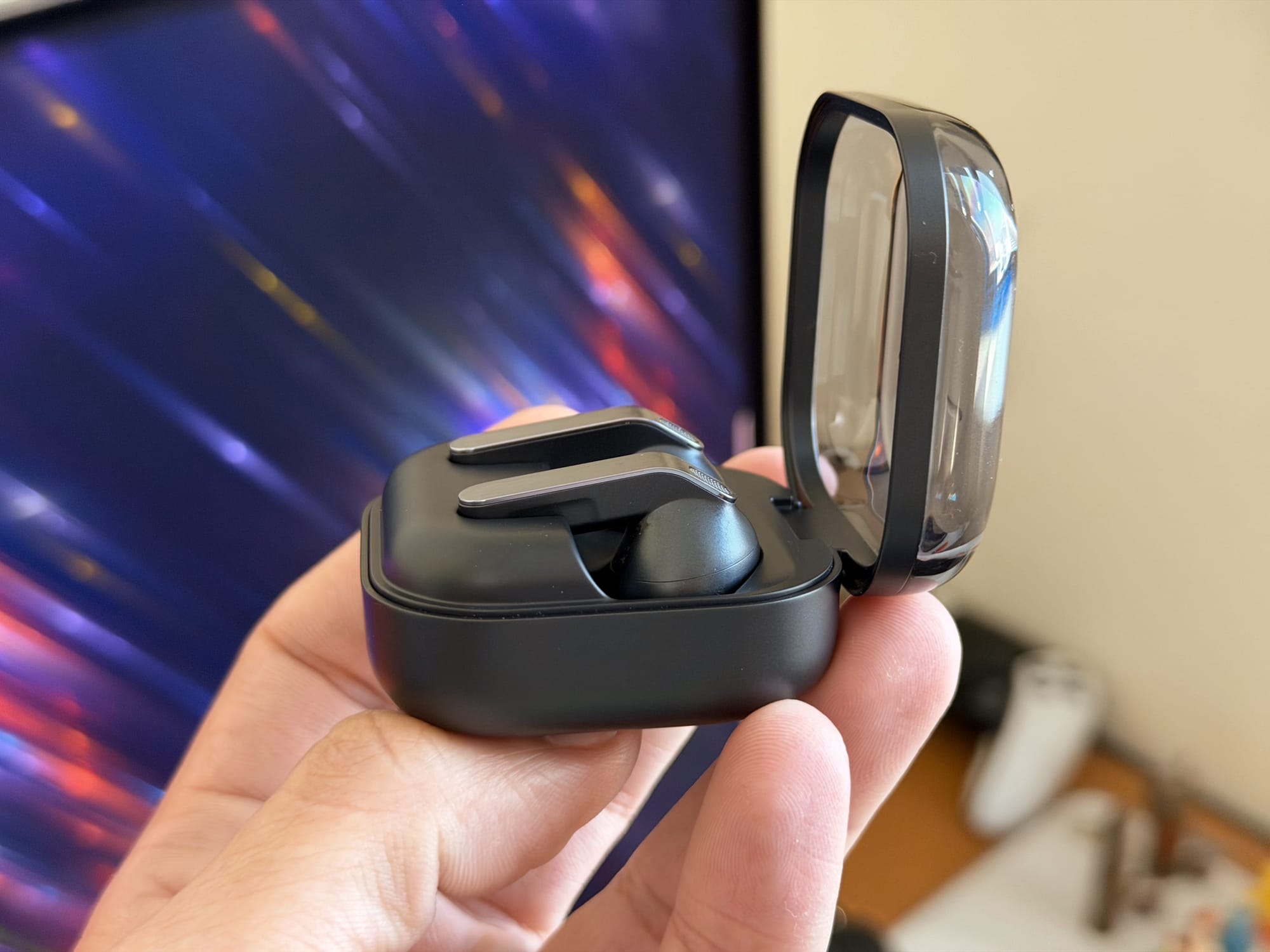 Hand holding Samsung Galaxy Buds4 Pro charging case from the side with earbuds partially visible.