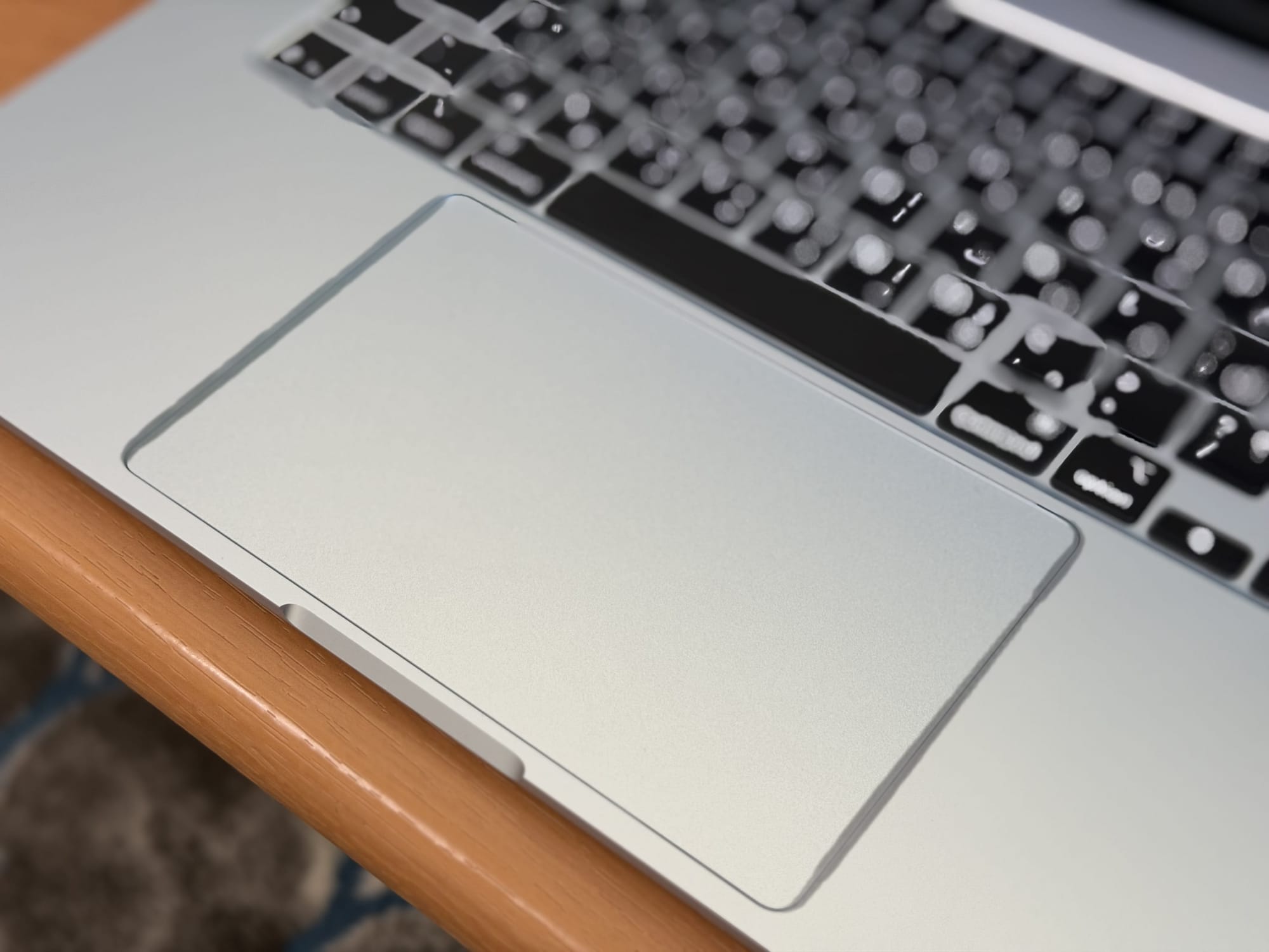 Close-up of the MacBook Air 15” trackpad and keyboard on a wooden surface.