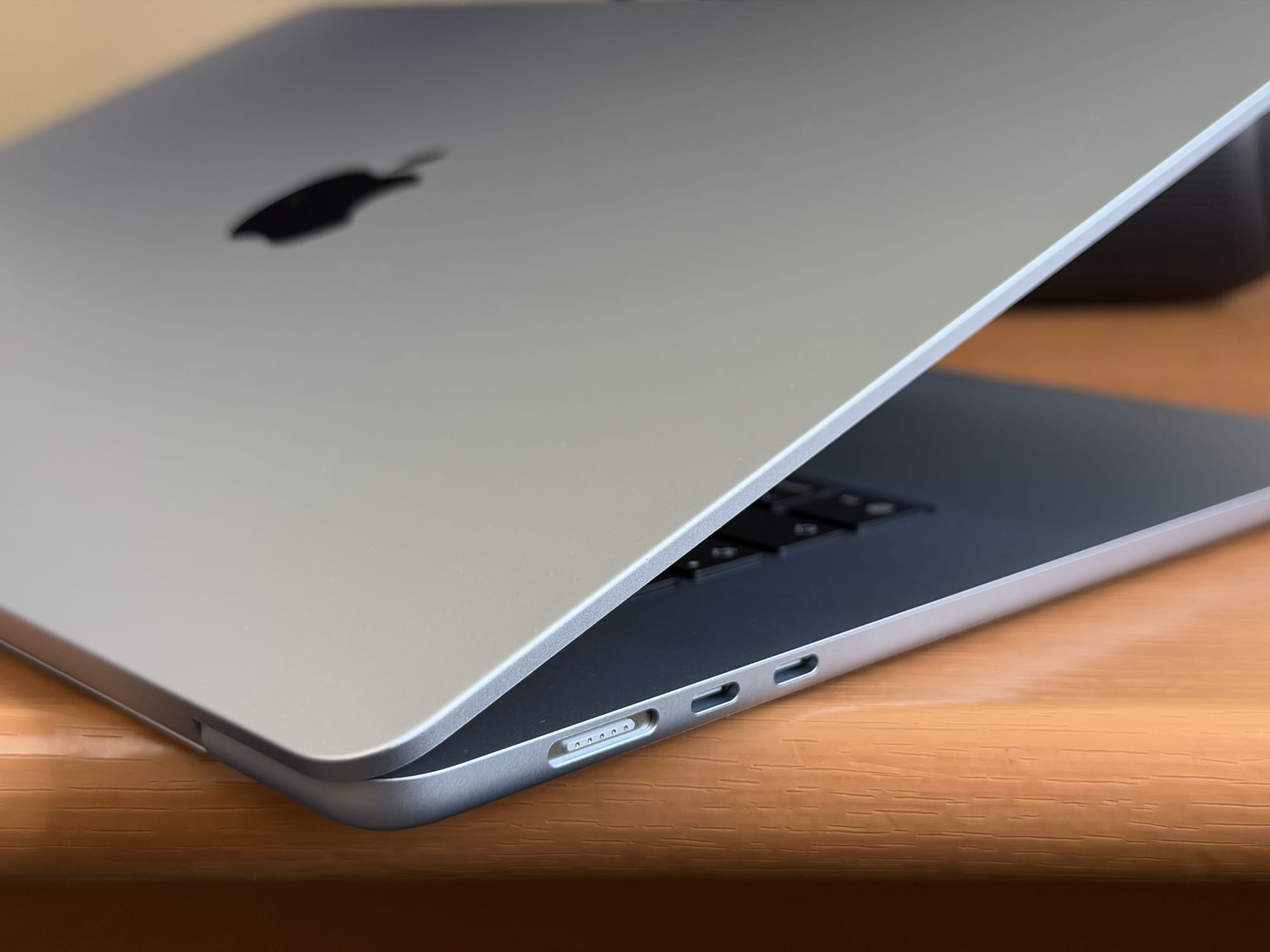 Side view of the MacBook Air 15” showing USB-C ports and partially open lid on a desk.