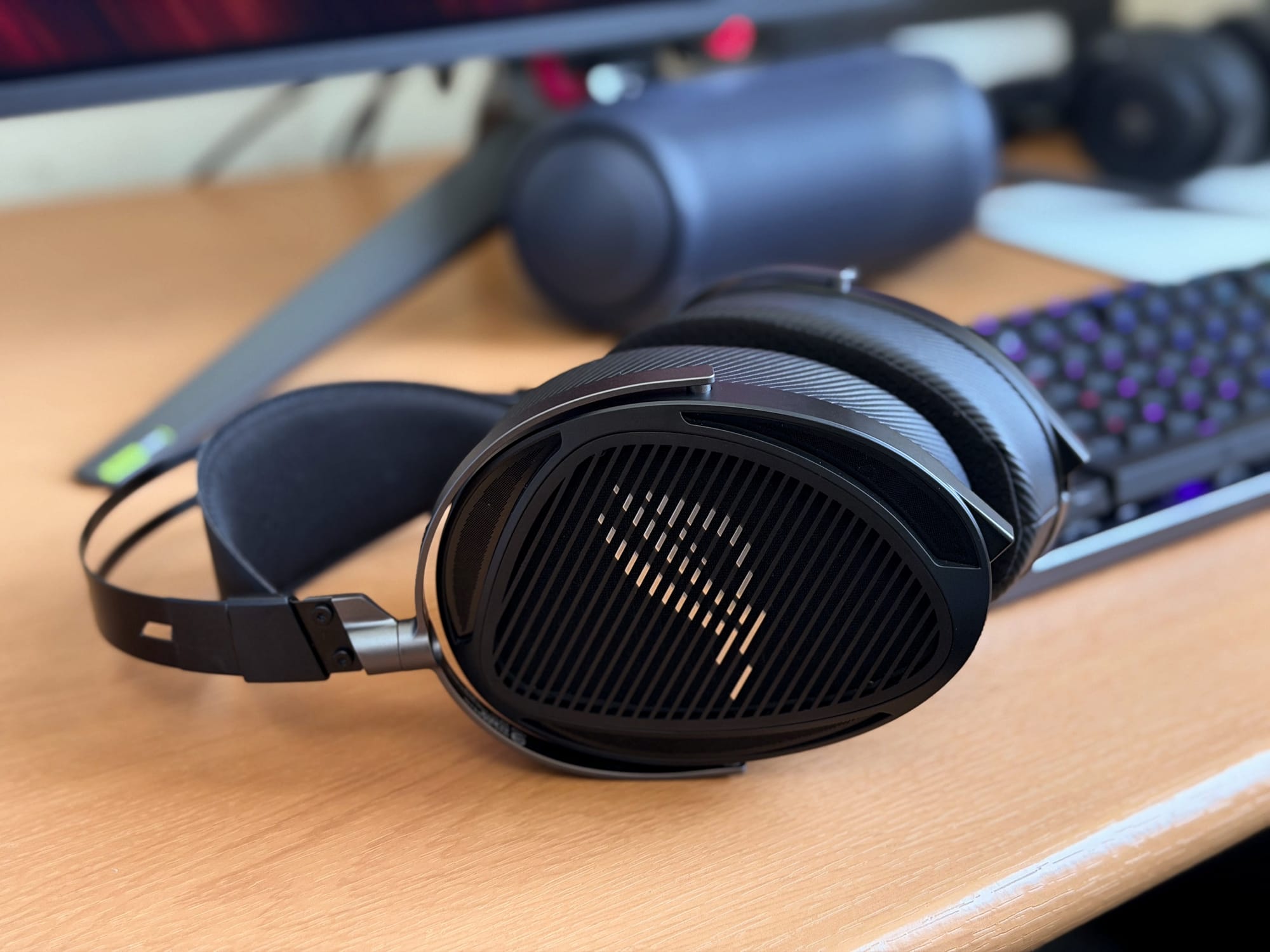Asus ROG Kithara headset resting on a desk beside a gaming keyboard and monitor.