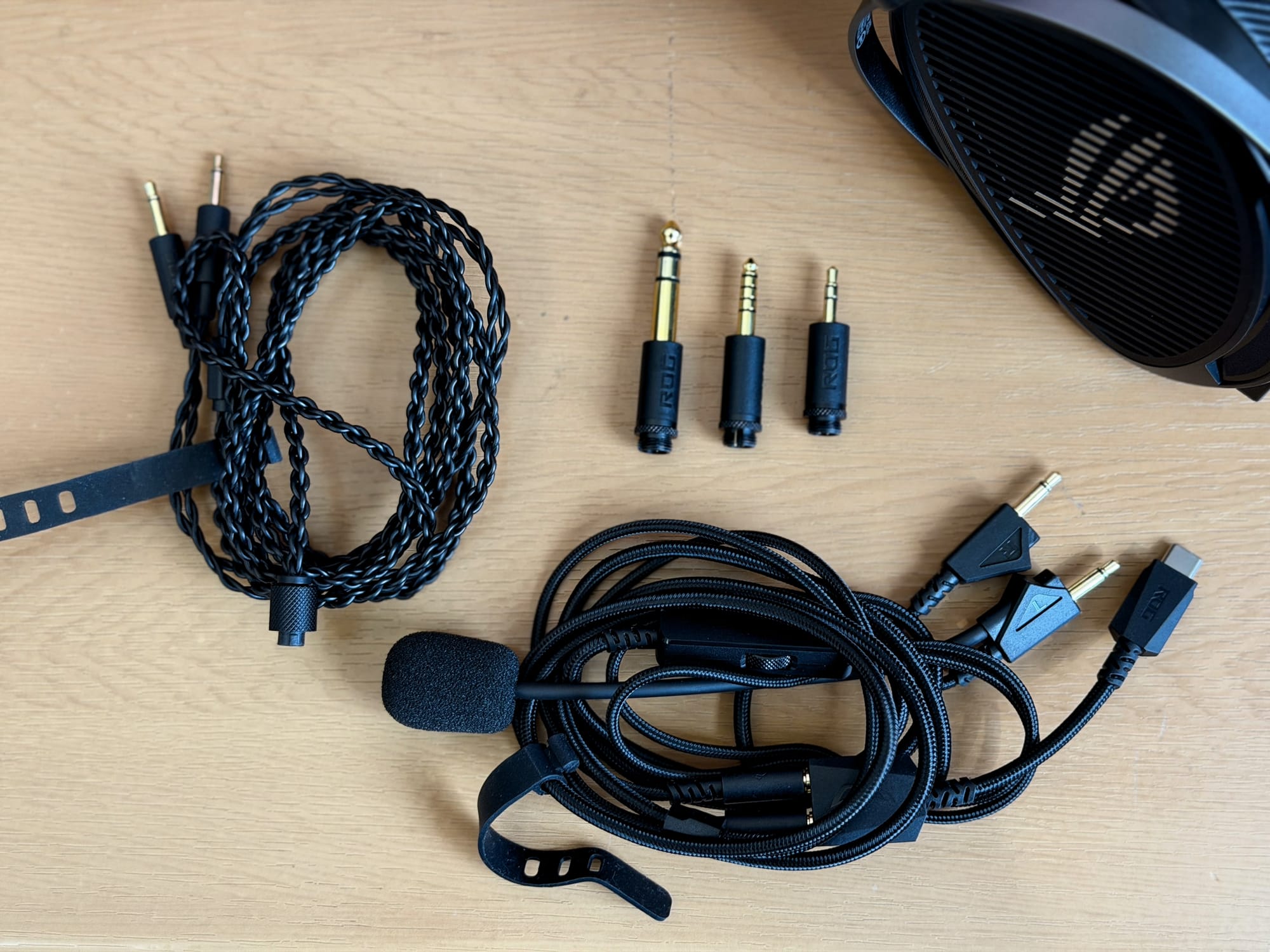 Various cables and connectors included with the Asus ROG Kithara headset on a table.