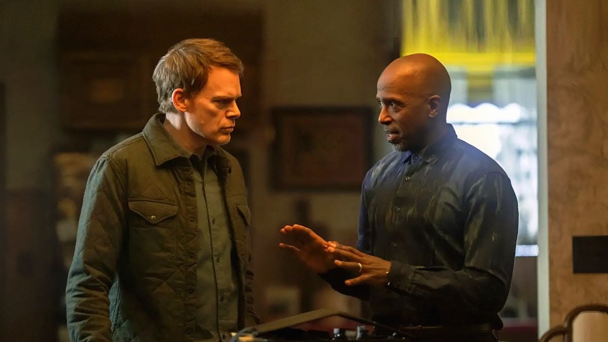 Michael C. Hall converses with a man in a blue patterned shirt, discussing serious matters.