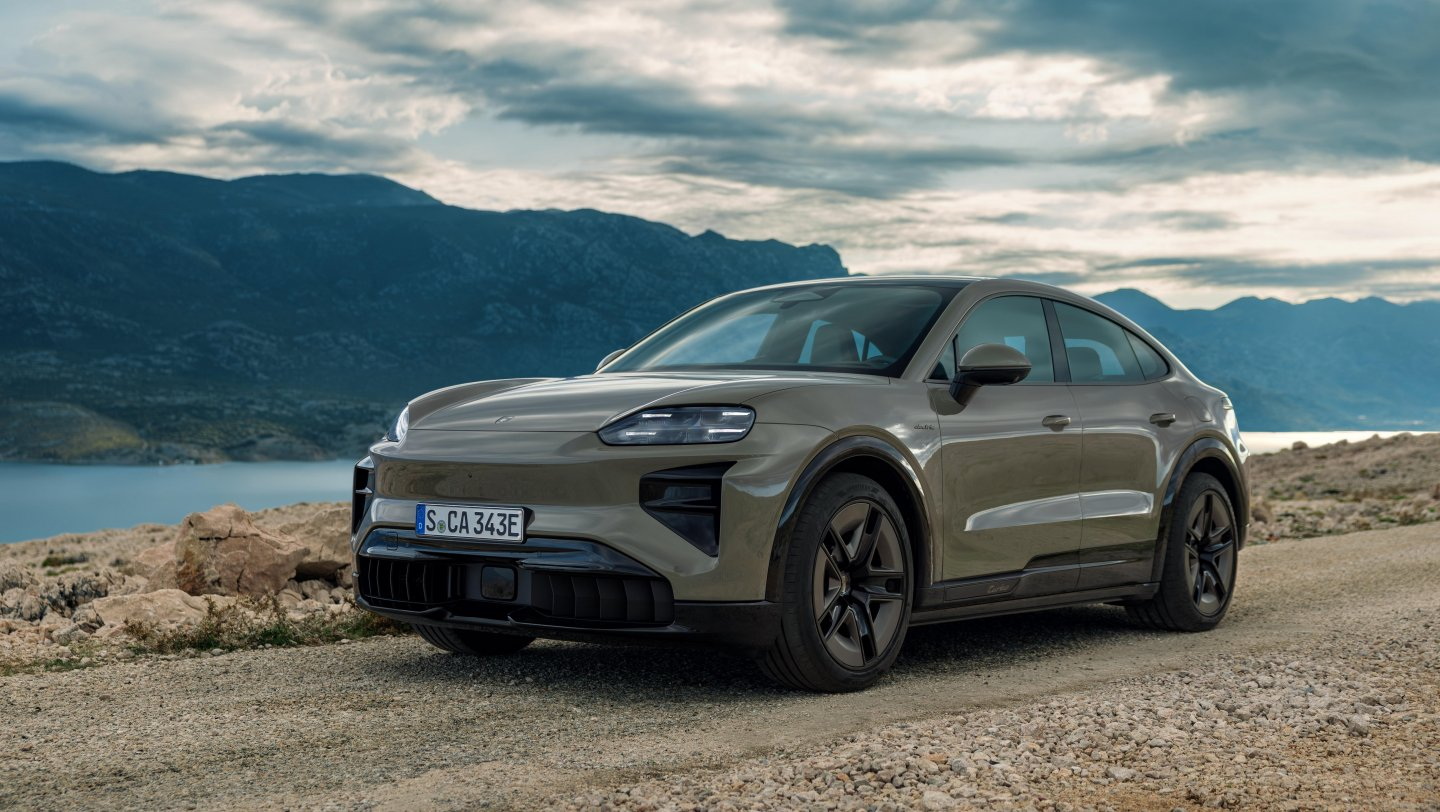 Porsche Cayenne Coupé Electric on a rugged road with a gray finish and mountainous backdrop.