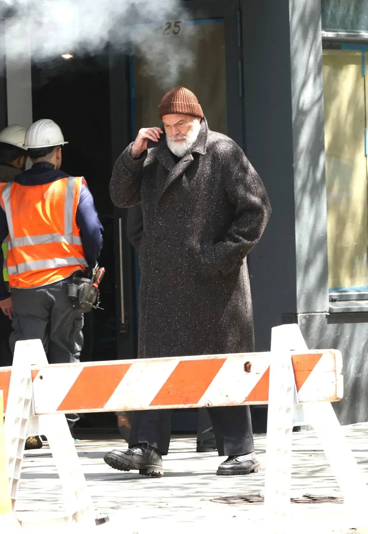 Kingpin on a city street, smoking a cigarette, surrounded by construction workers in safety vests.