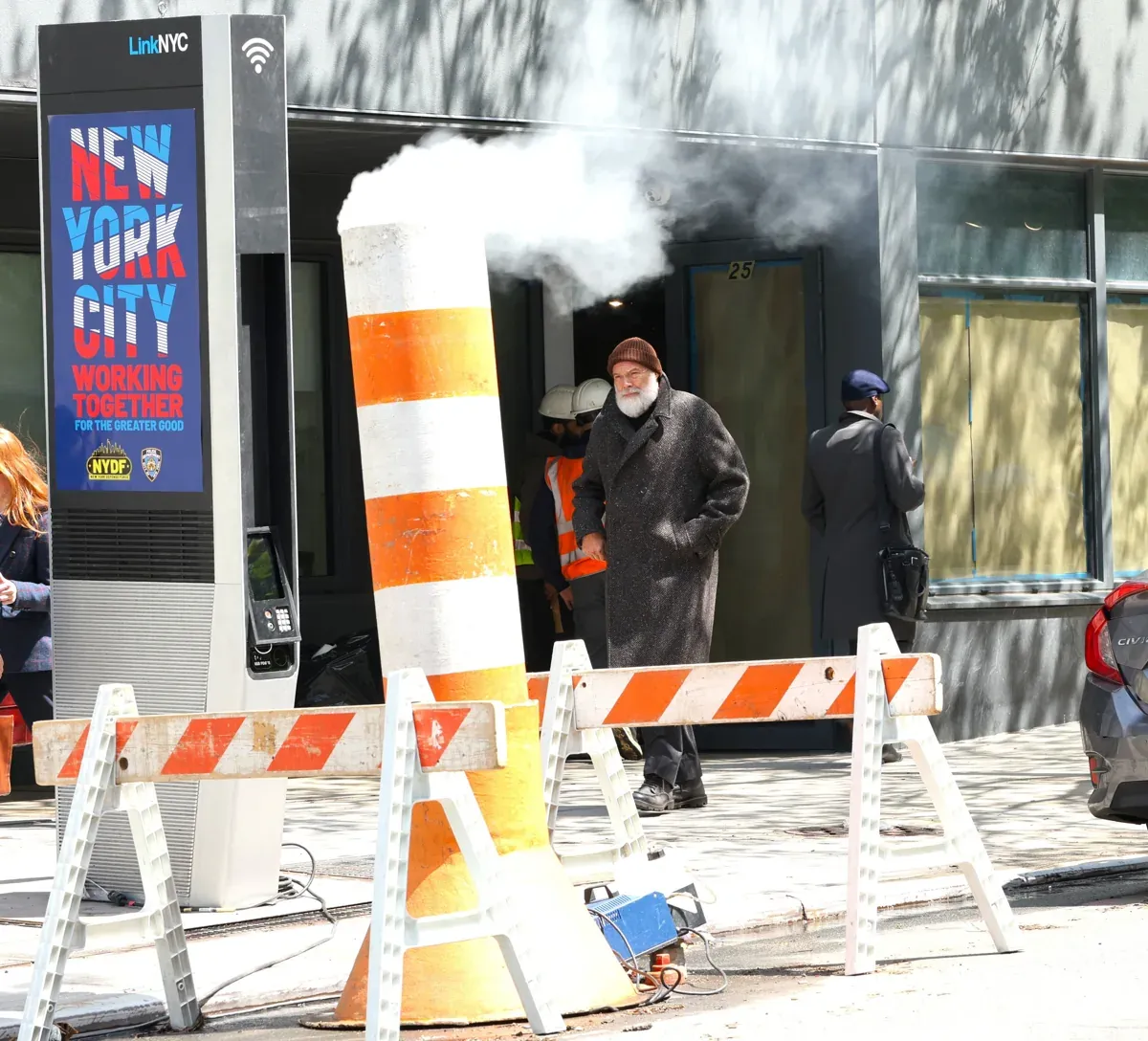 Kingpin at a city street's entrance marked with a smoke-emitting structure and construction signs.