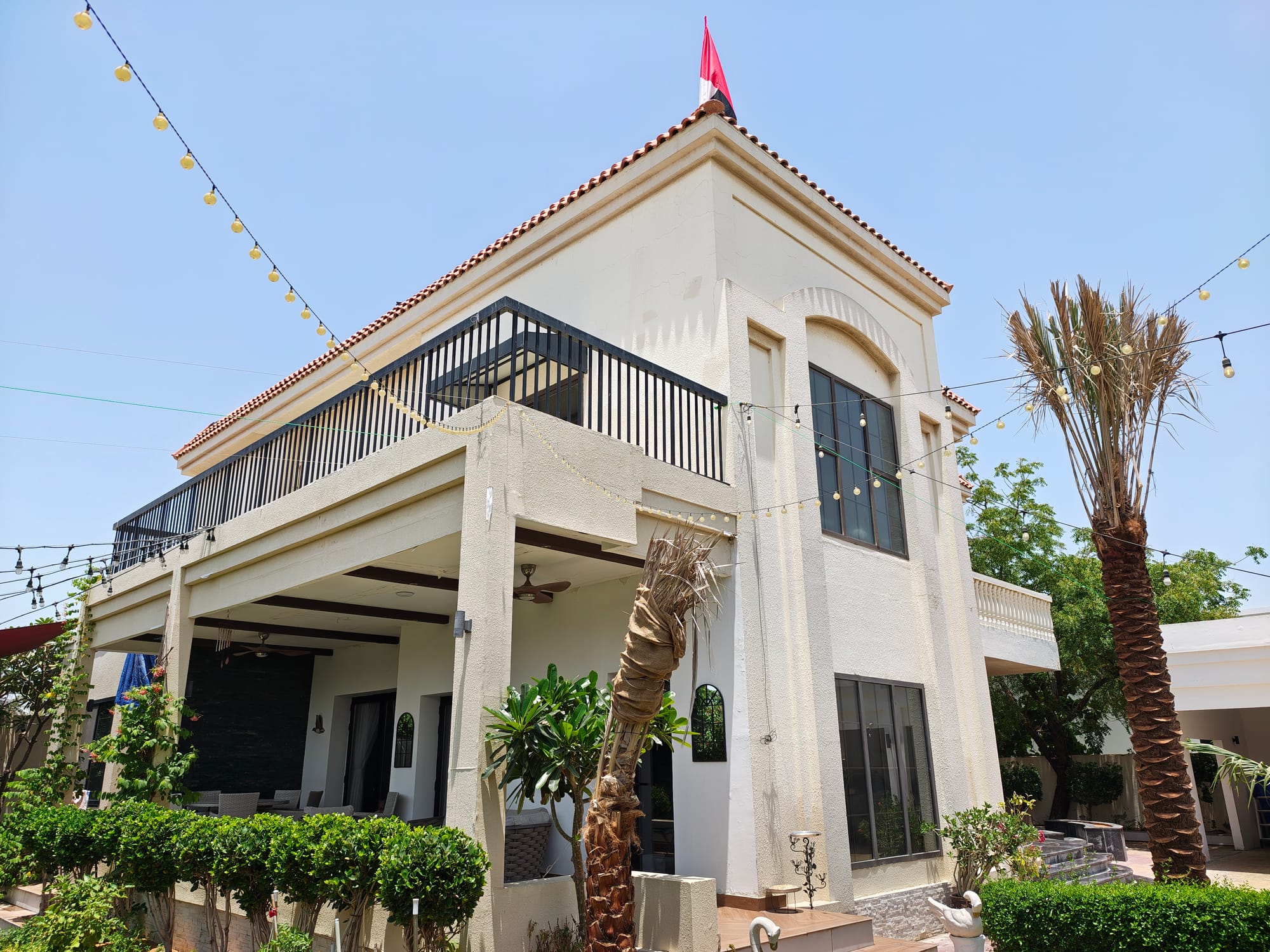 Exterior view of a modern house with palm trees and decorative lights.