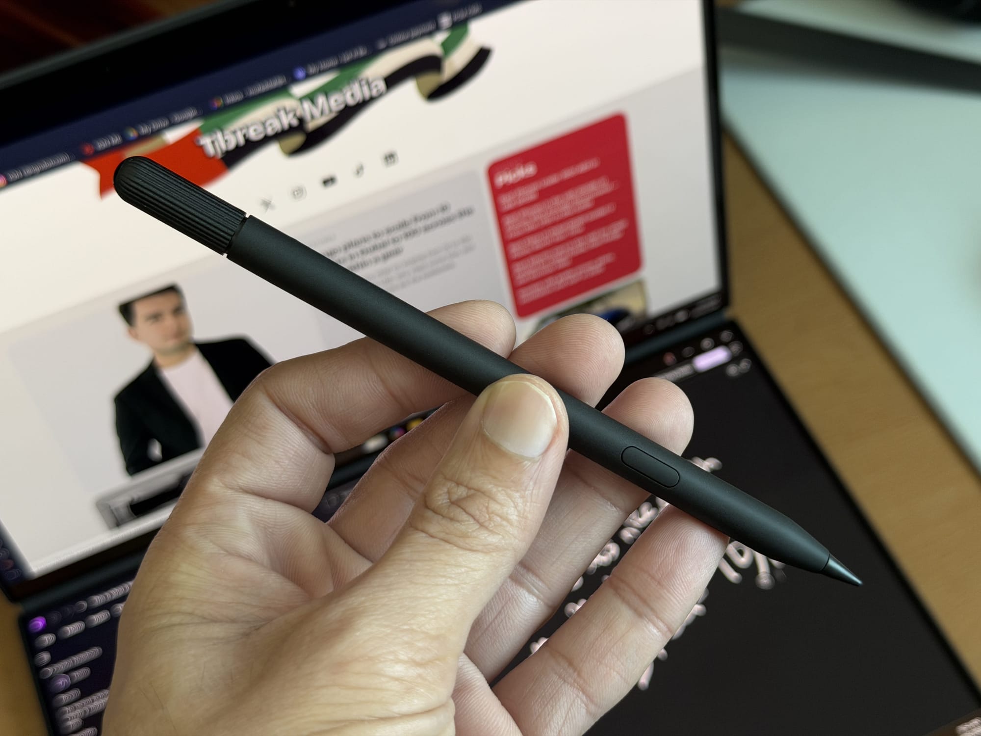 Hand holding an Asus stylus against the ZenBook Duo's screen showing a design interface.
