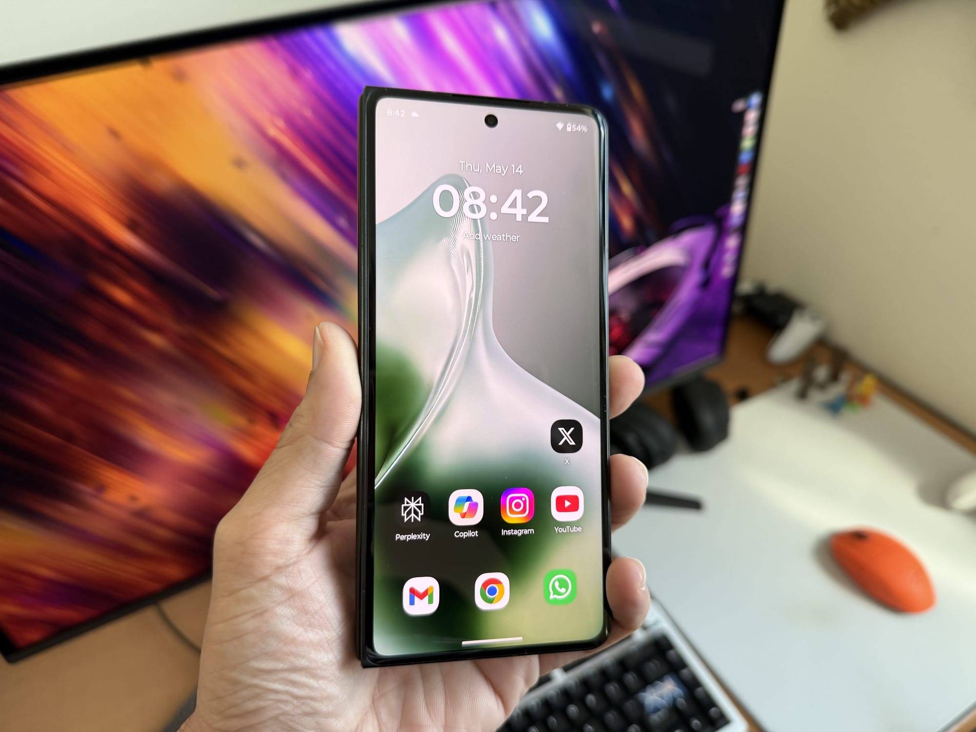 Motorola Razr Fold held upright, showing the home screen with apps open.
