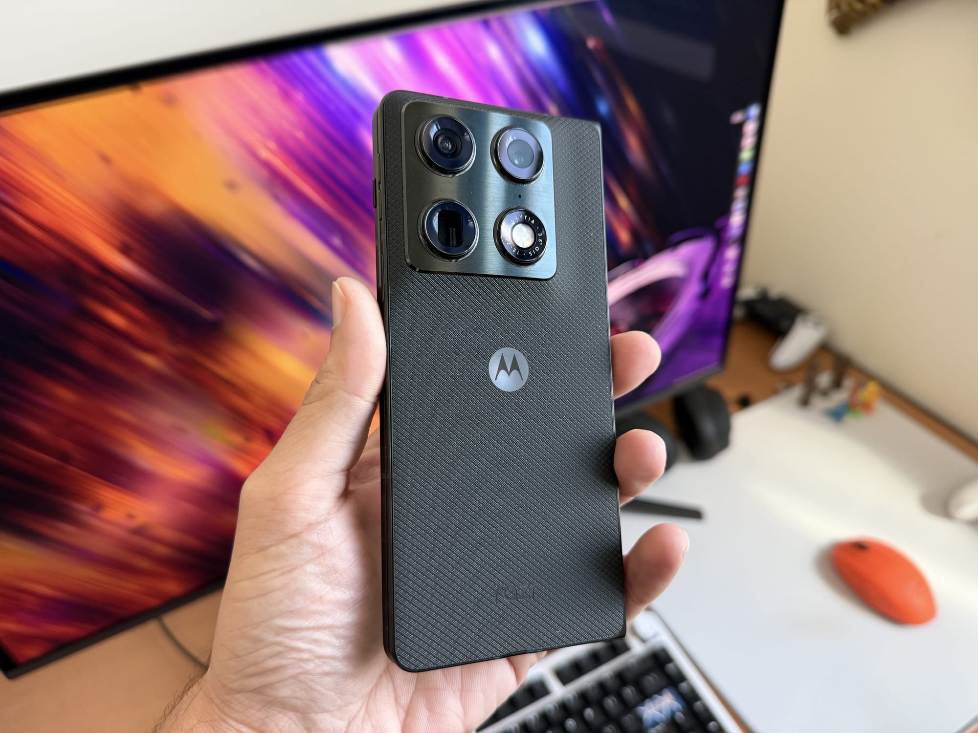 Motorola Razr Fold held in hand, showcasing the camera layout and textured back.