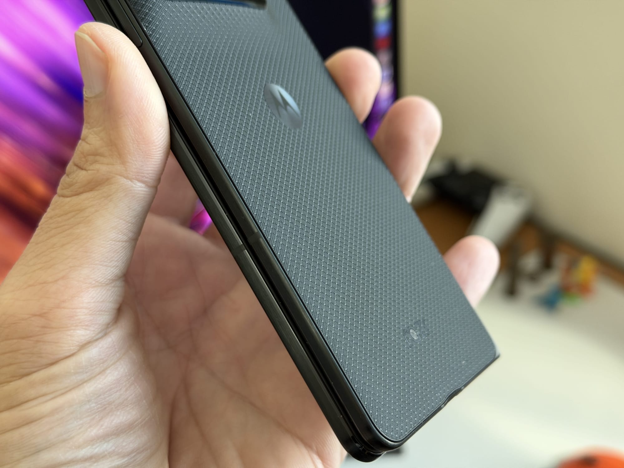Close-up of a user's hand holding the Motorola Razr showing its textured back and logo.