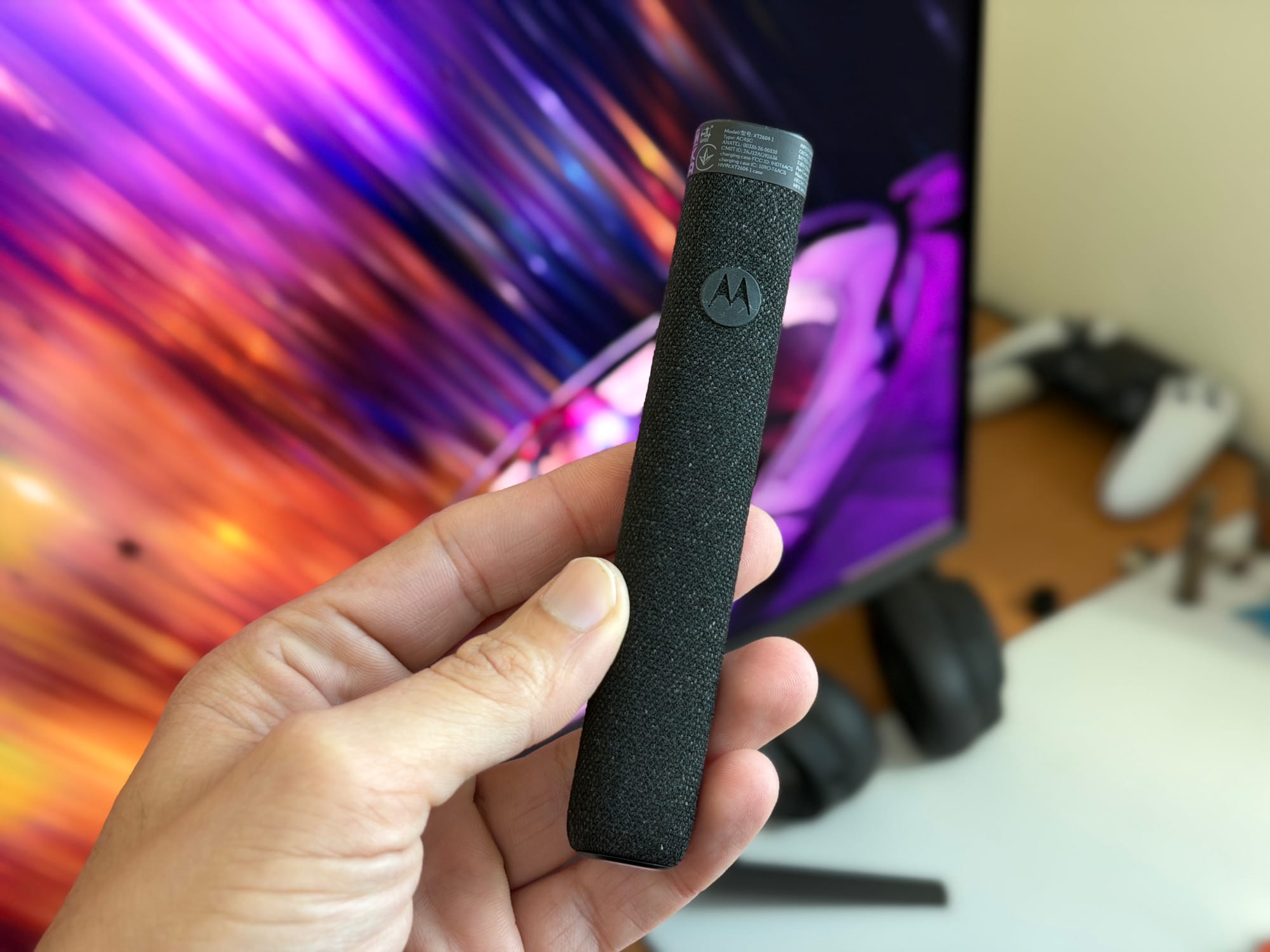 Motorola stylus pen being held over a blurred background of a computer screen.
