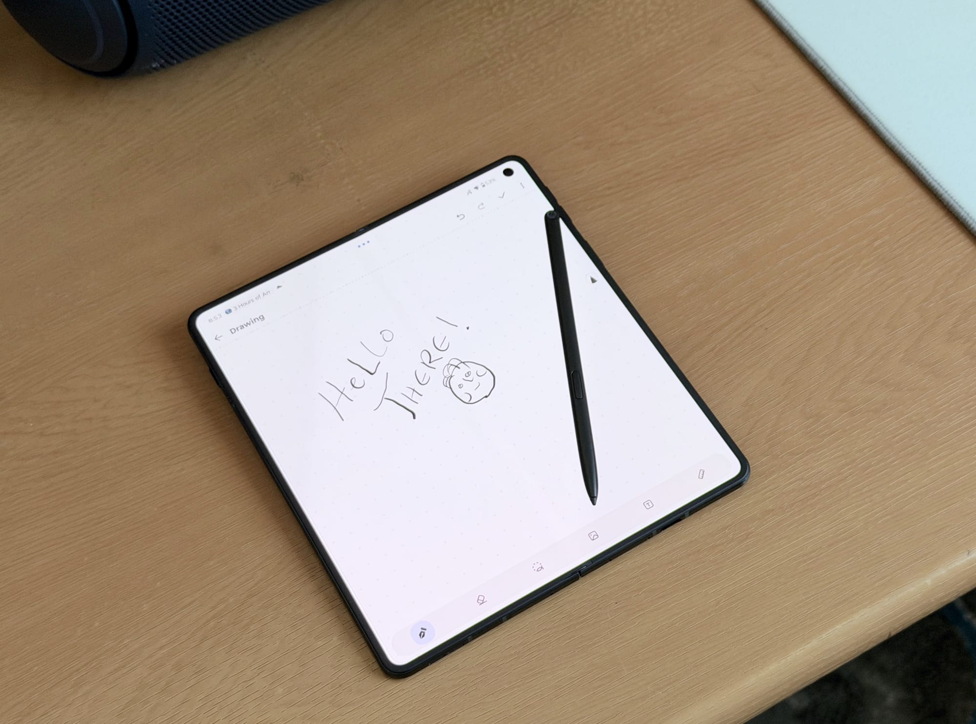 Motorola Razr folding phone displaying a handwritten note with a stylus on a wooden desk.