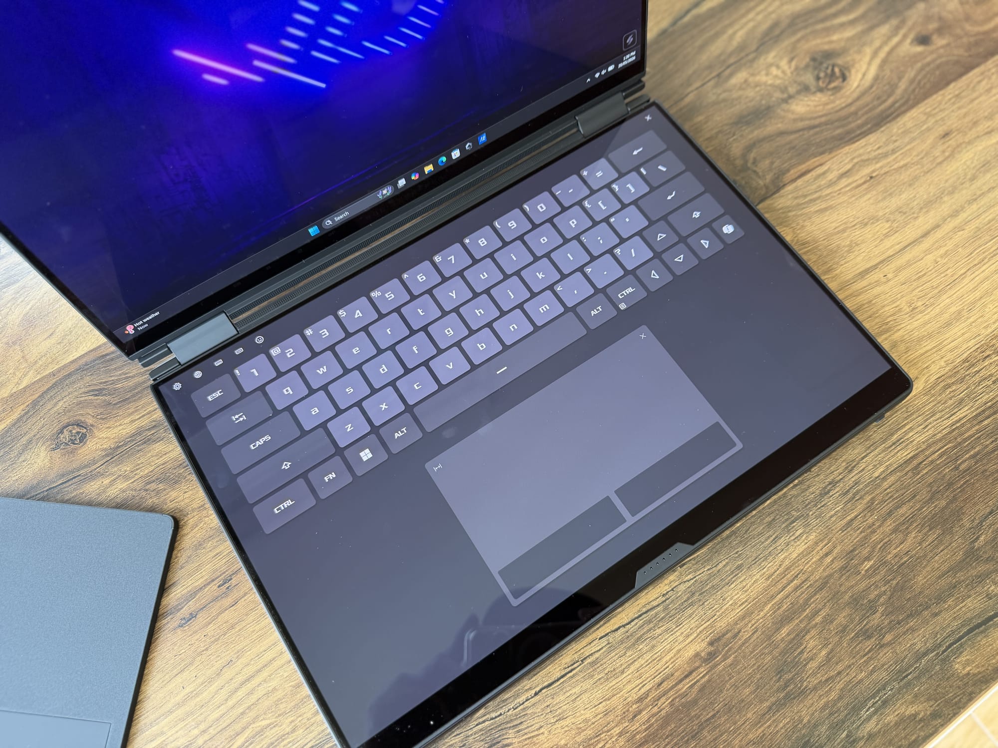 The lower OLED touchscreen showing an on-screen keyboard and trackpad, with the upper panel active