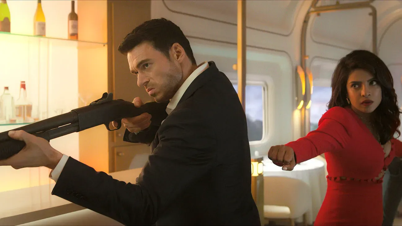 Intense confrontation with Priyanka Chopra Jonas and co-star, both armed, in a stylish interior setting.
