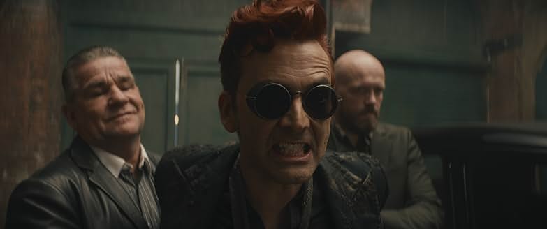 Crowley and two companions, with Crowley wearing sunglasses and expressing intensity.