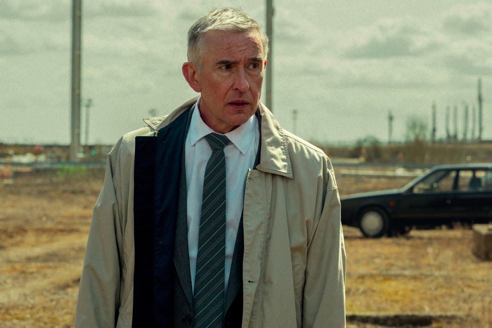 A man in a suit with a tie looks concerned while walking in a desolate landscape.