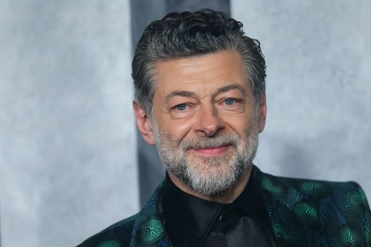 Andy Serkis smiling in a patterned suit at a premiere event.