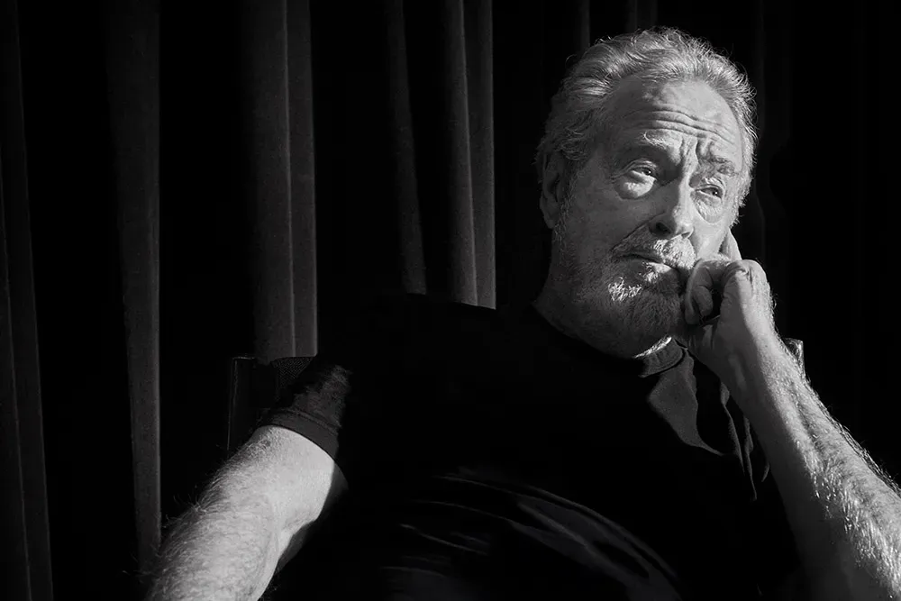 Ridley Scott seated in contemplation, captured in black and white with a thoughtful expression.