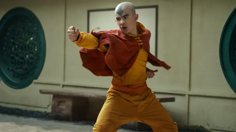Aang in orange and yellow attire performs a fighting stance in a dojo-like environment.