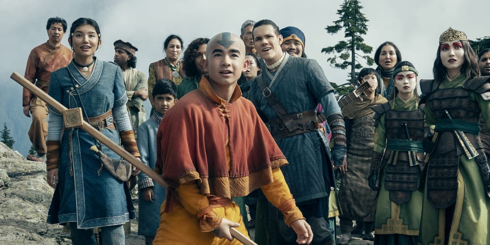A group of characters, including Aang, look amazed as they observe something in a mountainous area.