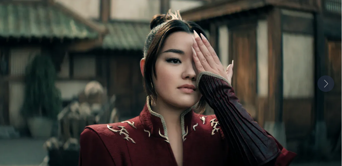 A character with one hand over an eye strikes a powerful pose in a traditional setting.