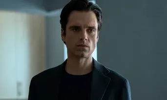 Sebastian Stan in a dimly lit room with a serious demeanor.