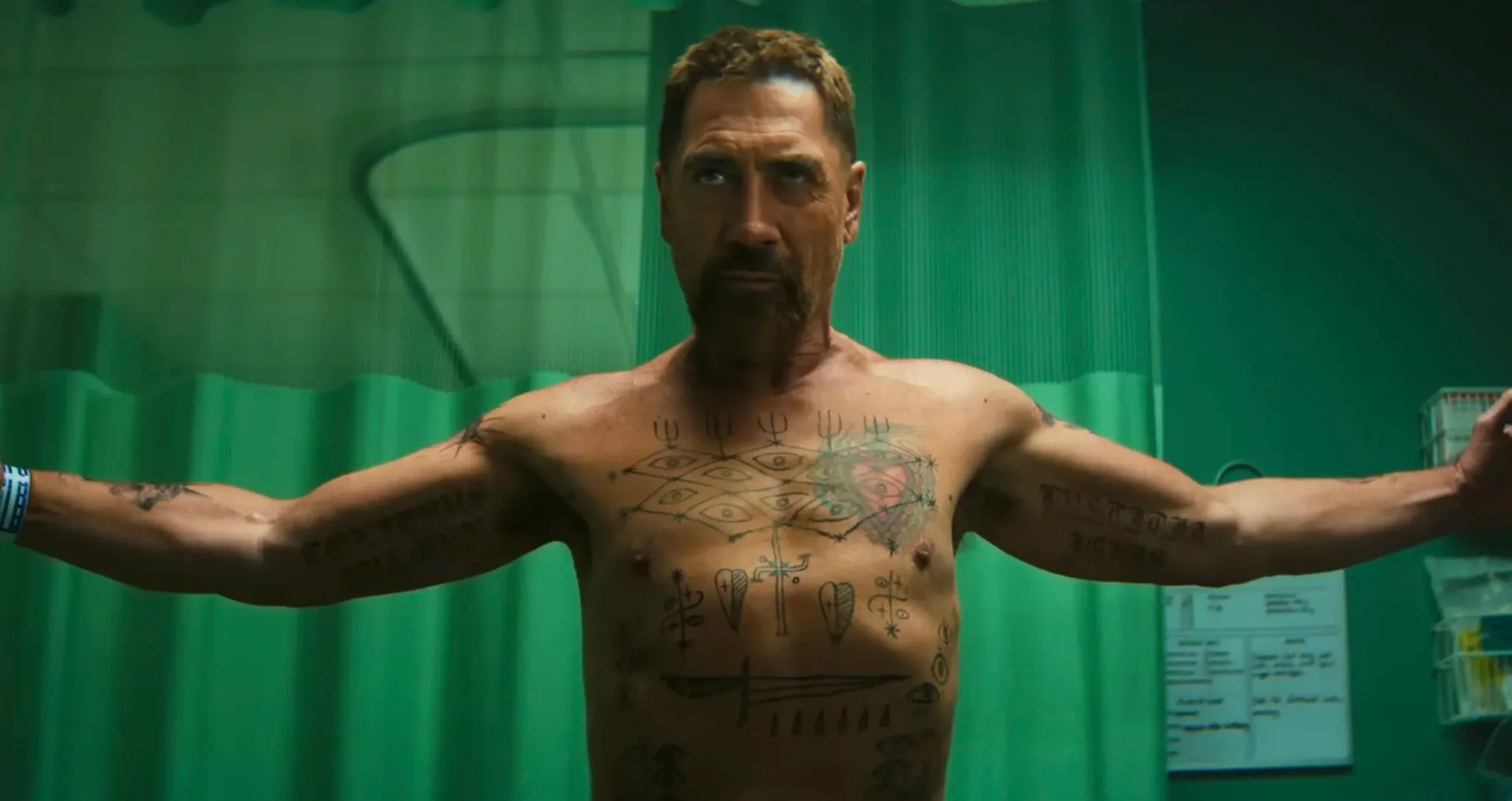 A tense moment showcasing a character with tattoos in a medical setting.