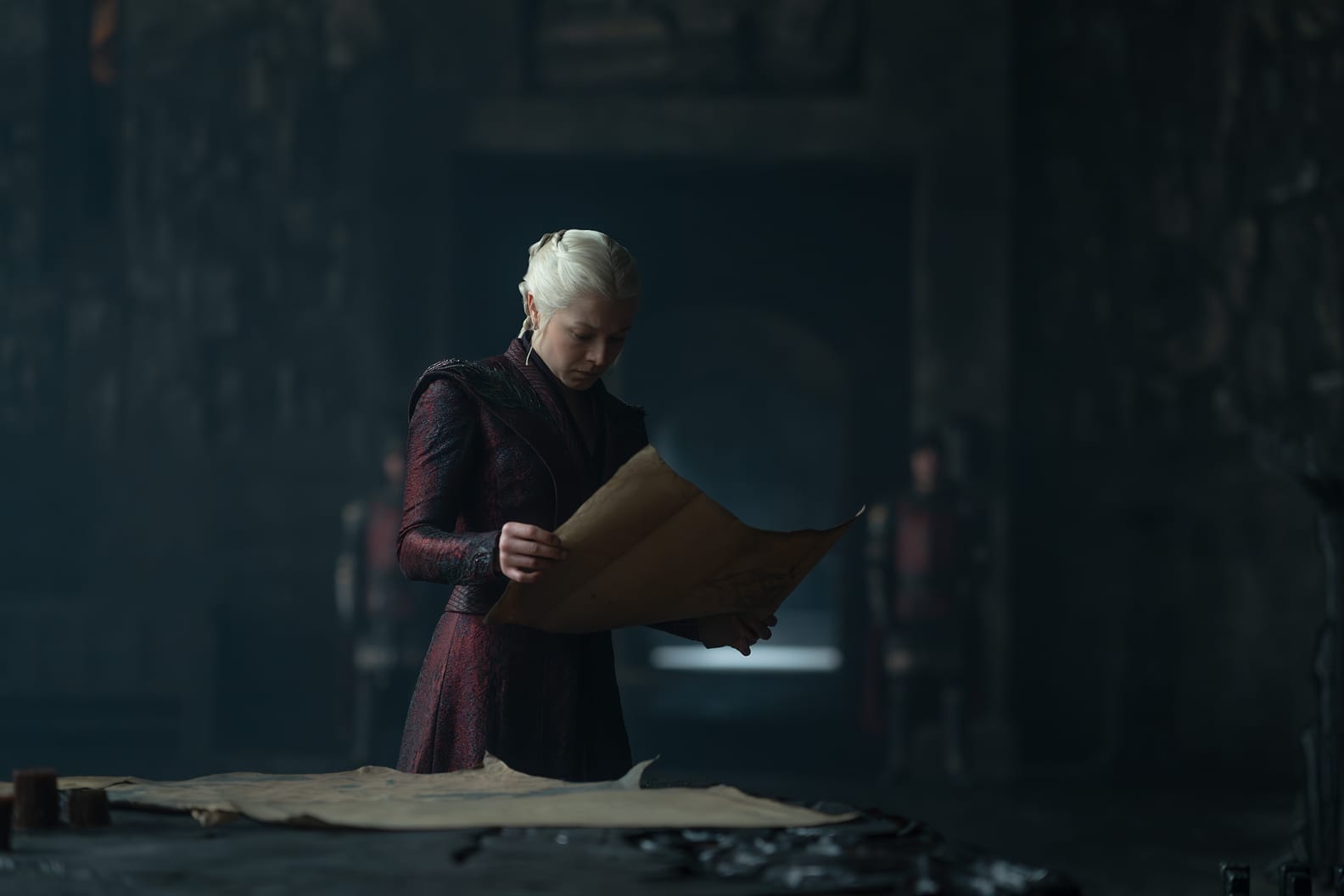 A character reading a large map in a dimly lit room, with a focus on the written details.