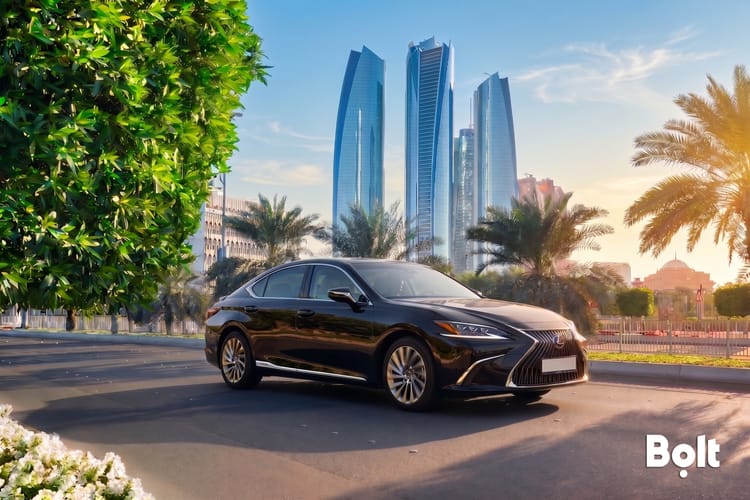 Smartphone ride-hailing app beside a car in Abu Dhabi