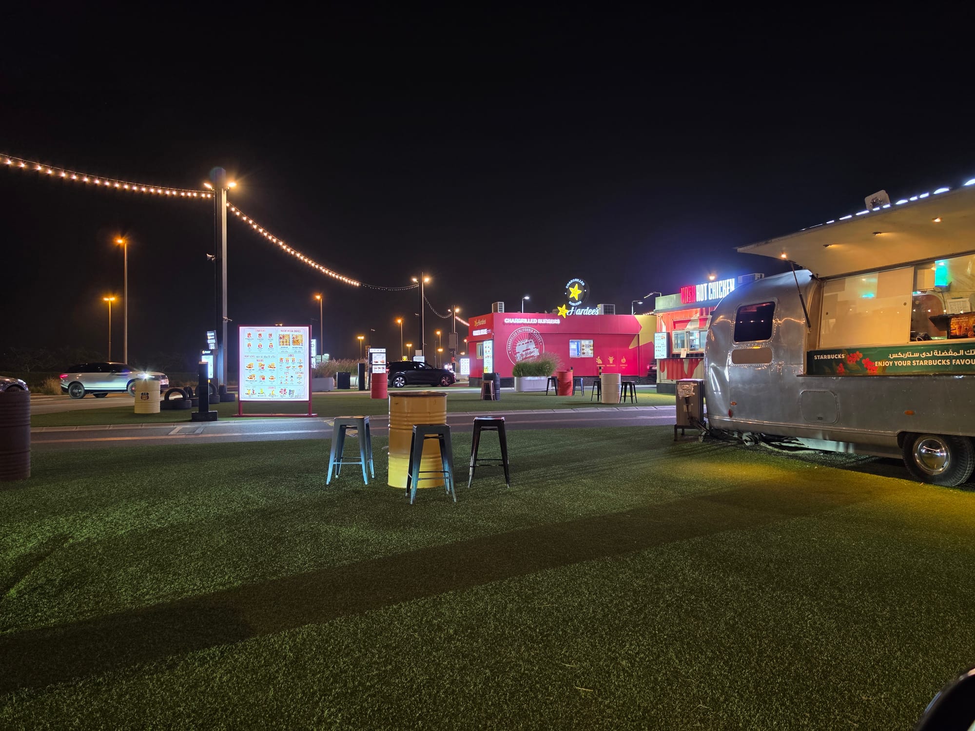 Outdoor scene featuring a food truck and nearby illuminated storefronts at night, with a focus on a table.