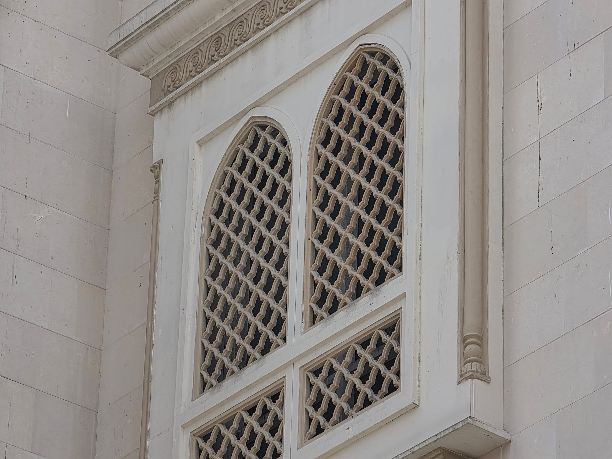 Detail of a decorative window in the mosque, featuring intricate lattice work.
