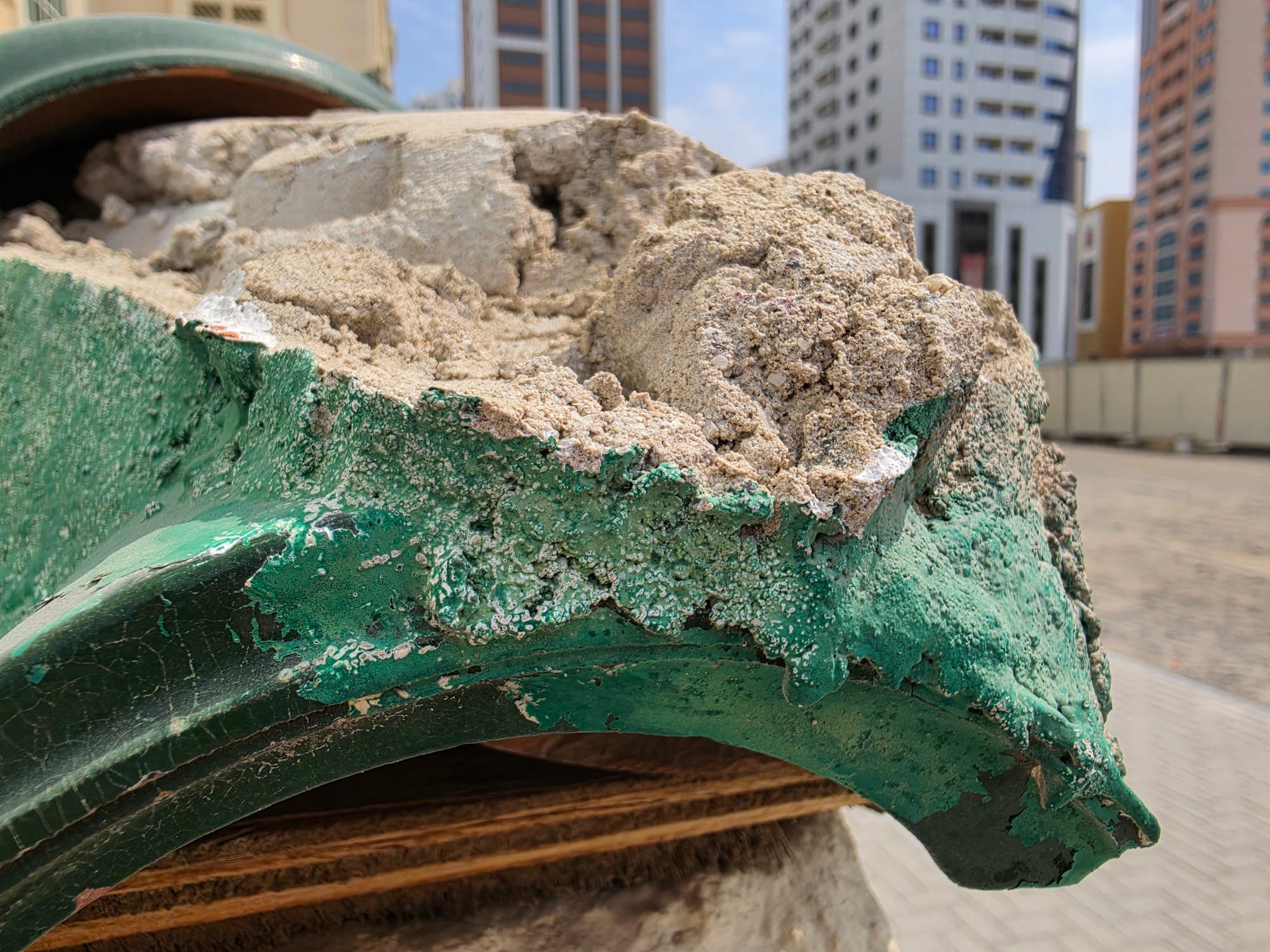 Close-up of weathered paint on a large green structure, displaying texture and damage.