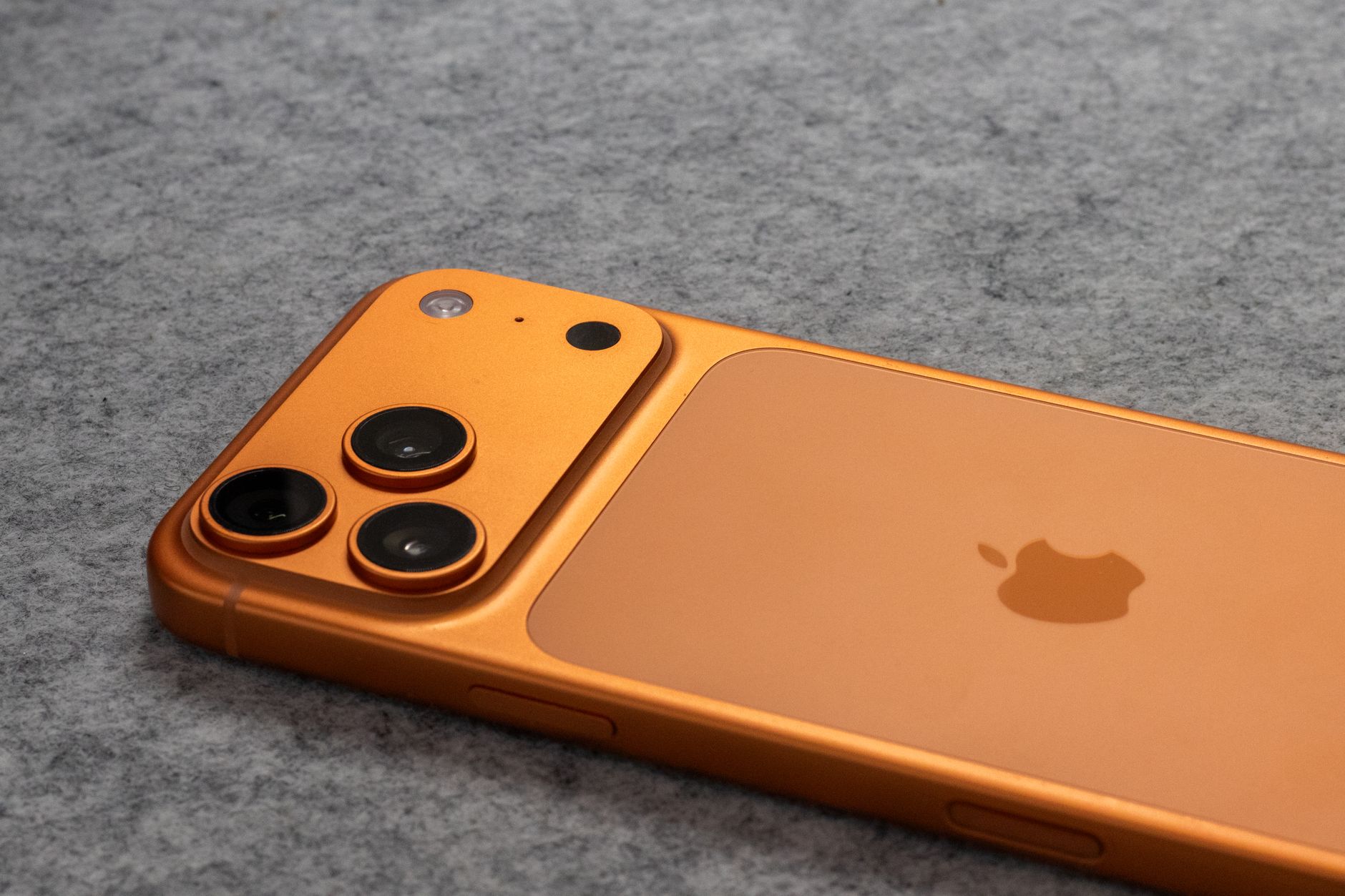 orange smartphone with dual cameras on gray surface