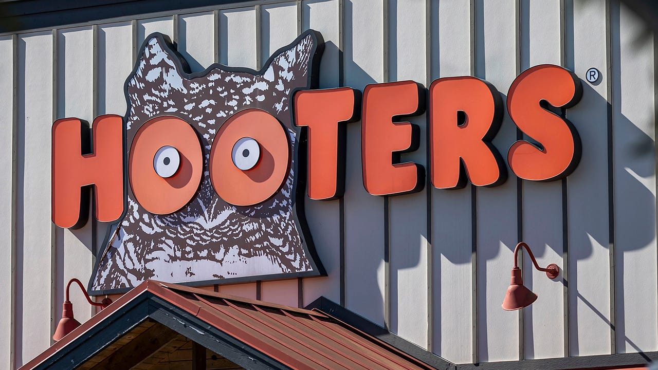 The Hooters restaurant owl logo sign on a white building facade
