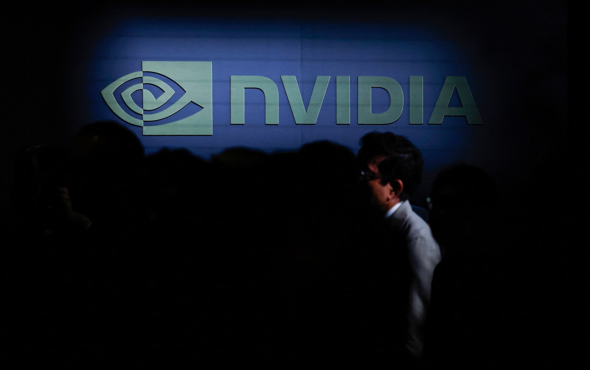 Nvidia CEO Jensen Huang at a company event with the glowing Nvidia logo behind him