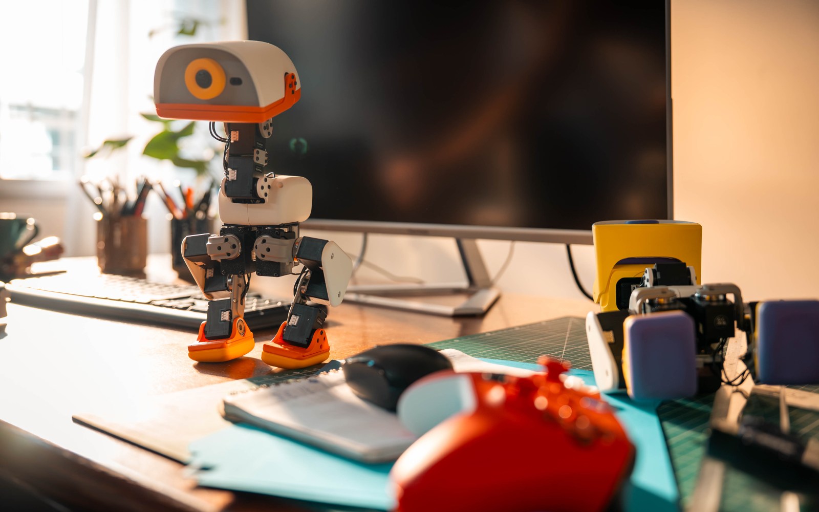 Hugging Face Microduck duck robot standing on a desk in warm morning light