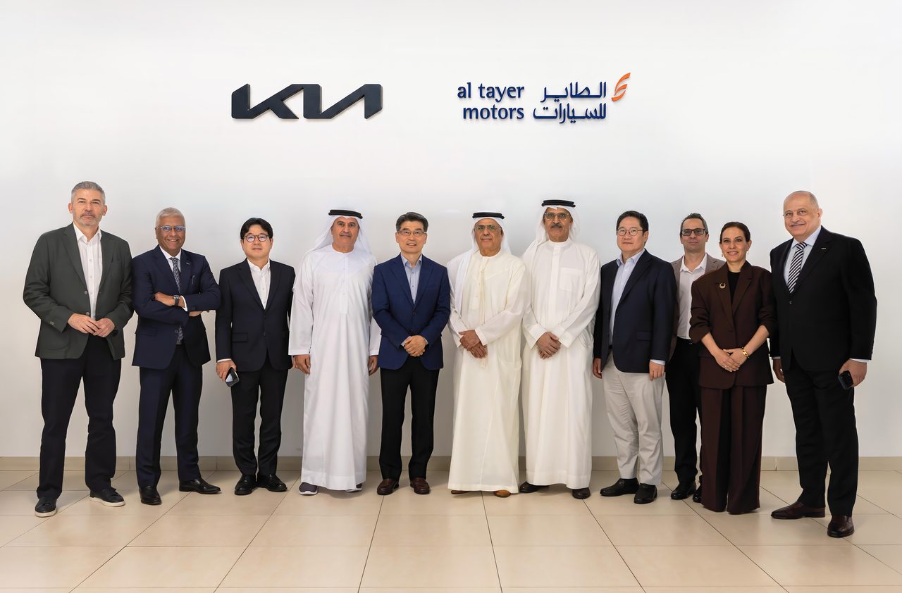 Kia and Al Tayer Motors executives standing under Kia and Al Tayer Motors logos at the UAE distributor announcement